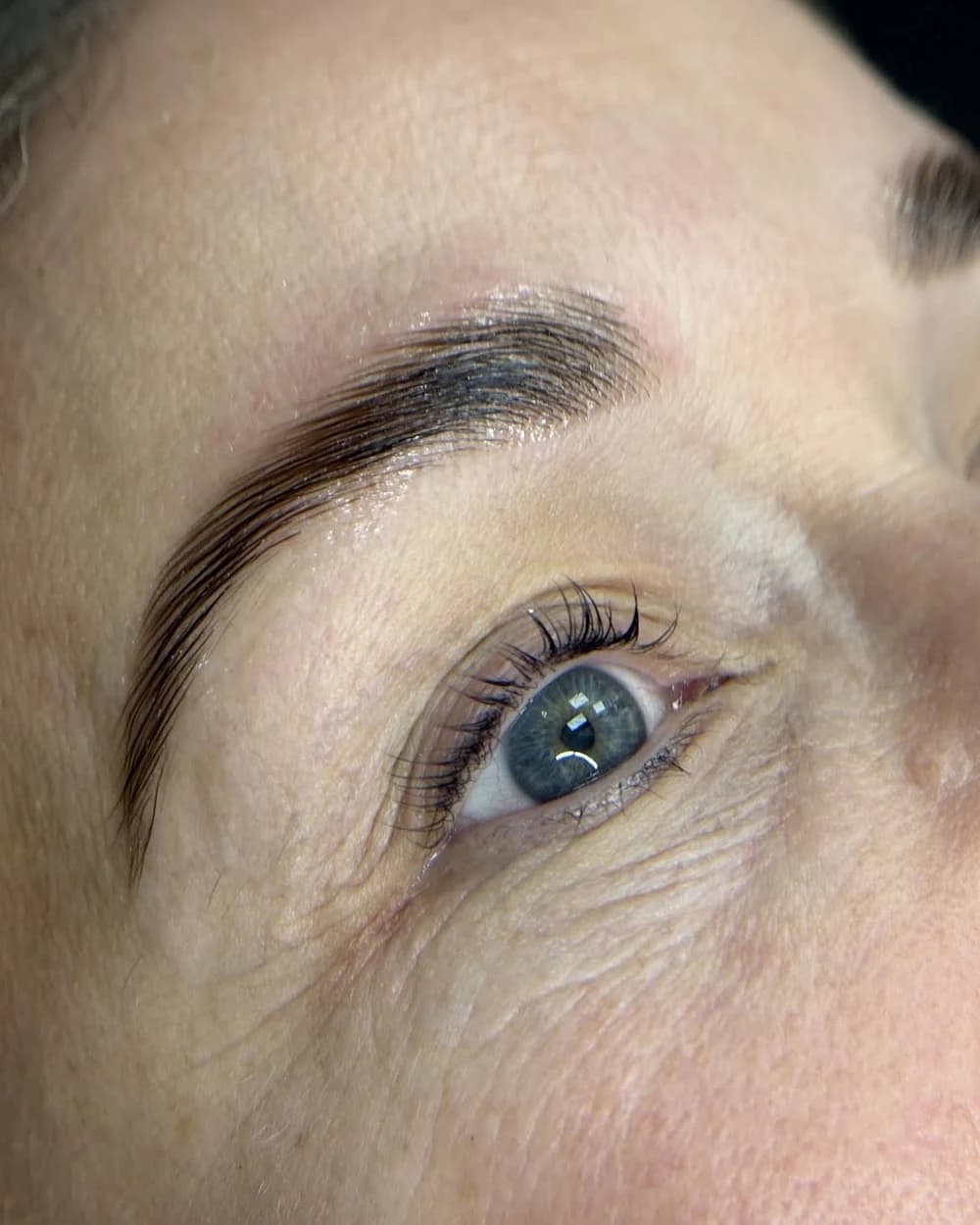 Cejas laminadas sobre piel madura, ojo azul